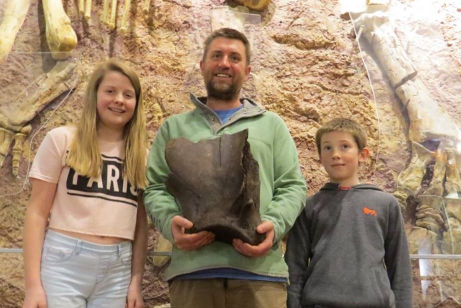 Mr Hollingshead and kids holding extinct elephant shoulder bone fossil