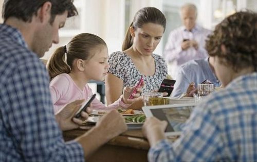 Family eating using smartphones