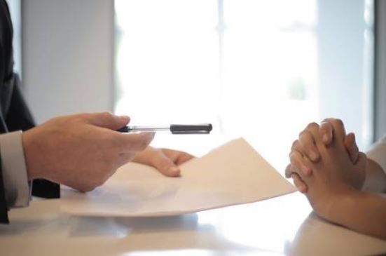 Get compensated after an accident - lawyer handing a pen to a client