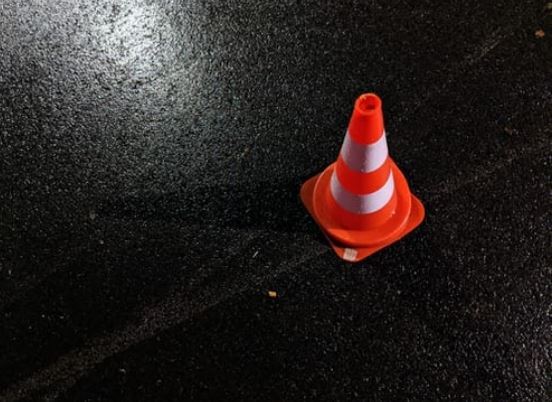 Get compensated after an accident - traffic cone on a dark road surface