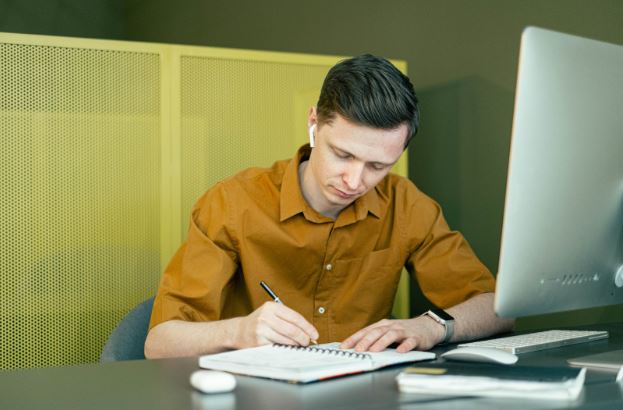 Man at a desk writing - image 4444