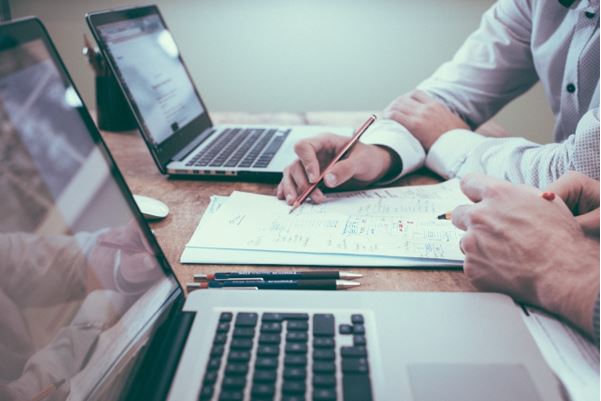 Two people at a desk reading something on a sheet of paper