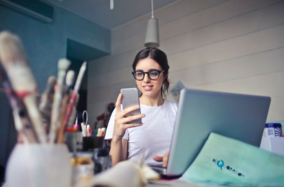 Woman at desk looking at her mobile phone - investment diversification article 44