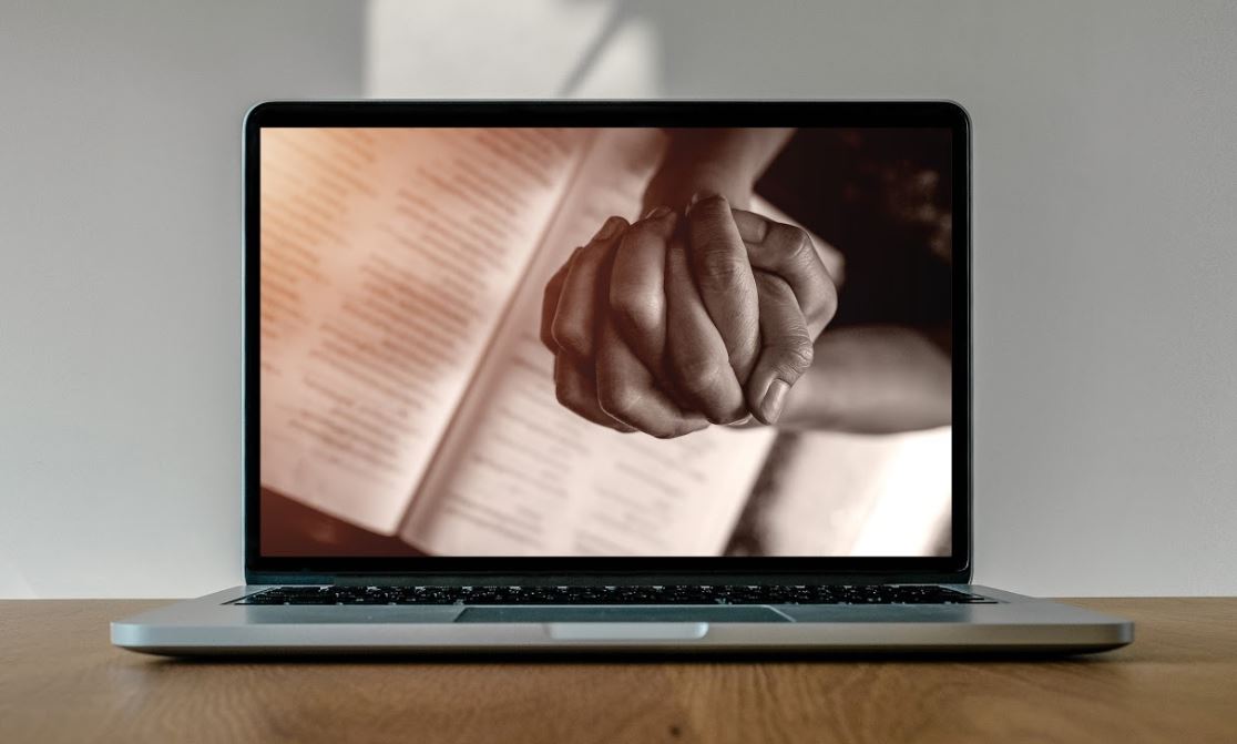 Laptop with image of hands in prayer position - 498938948