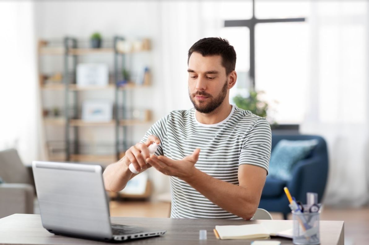 Man using hand sanitizer at desk