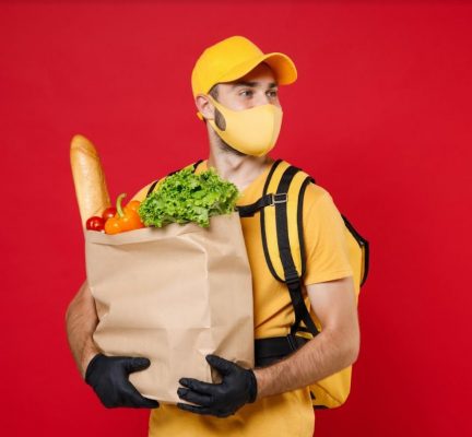 Man wearing mask carrying groceries in paper bag