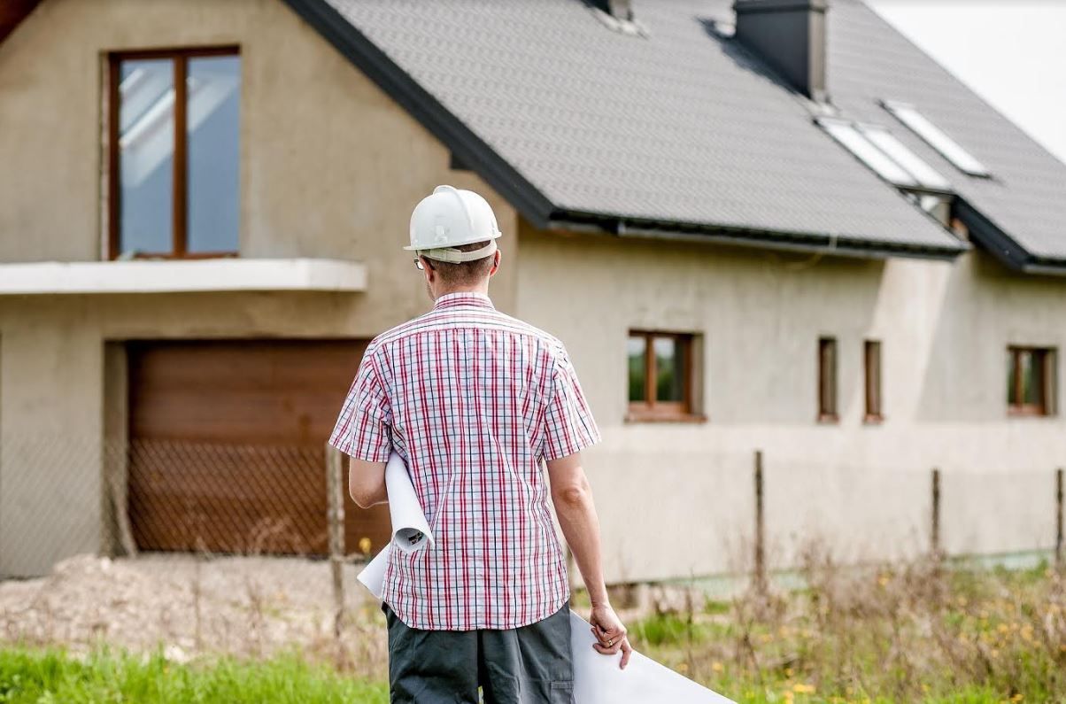 Home warranty article - man standing in front of new house