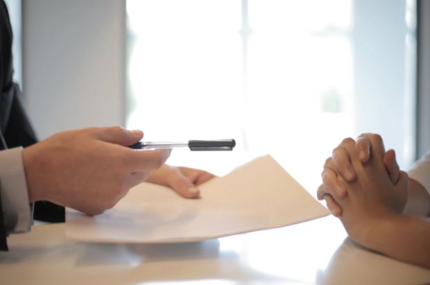 Agent handing pen and paper for client to sign