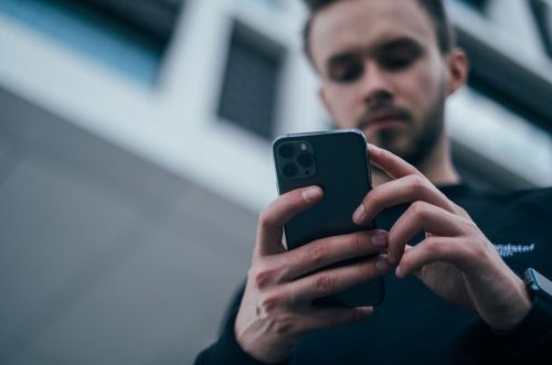 Man looking at his mobile phone - article about understanding insurance policy numbers