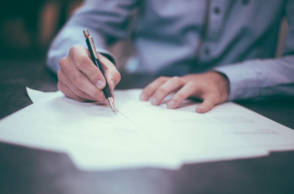 Man writing at desk - insurance policy numbers article