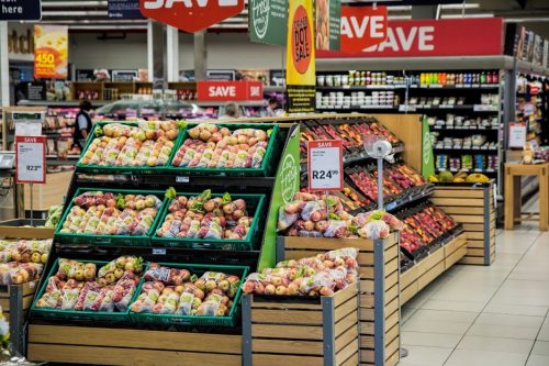 Produce display stands advertise apples in the centre of a grocery store.