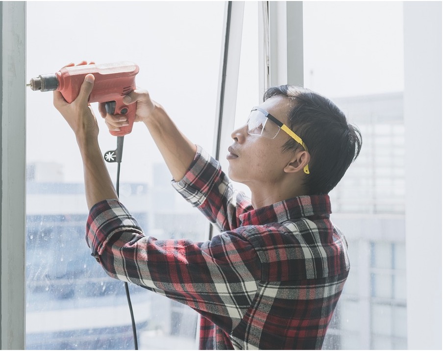 A man with a drill wearing prescription safety glasses