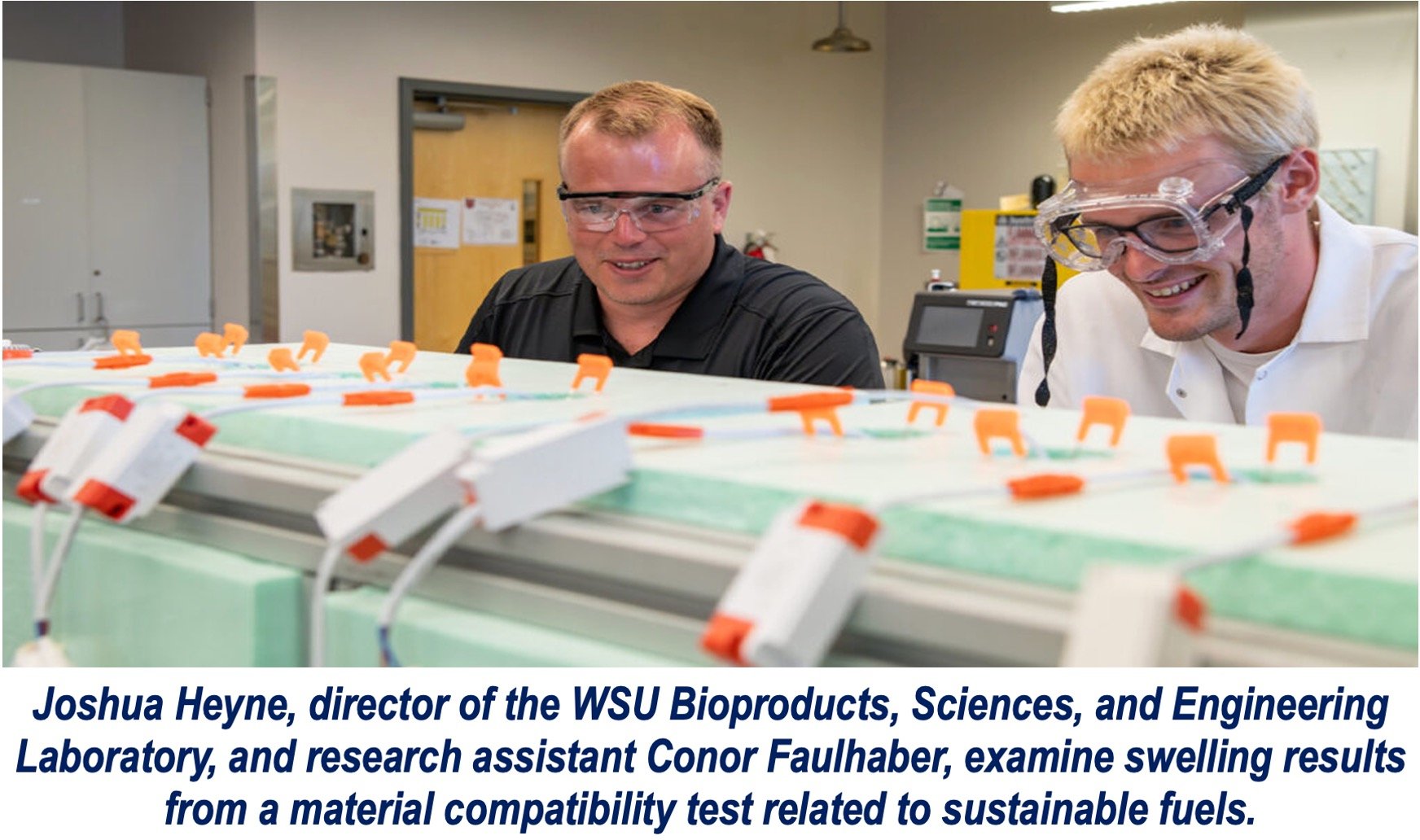 Image of two scientists in a lab, they are smiling.