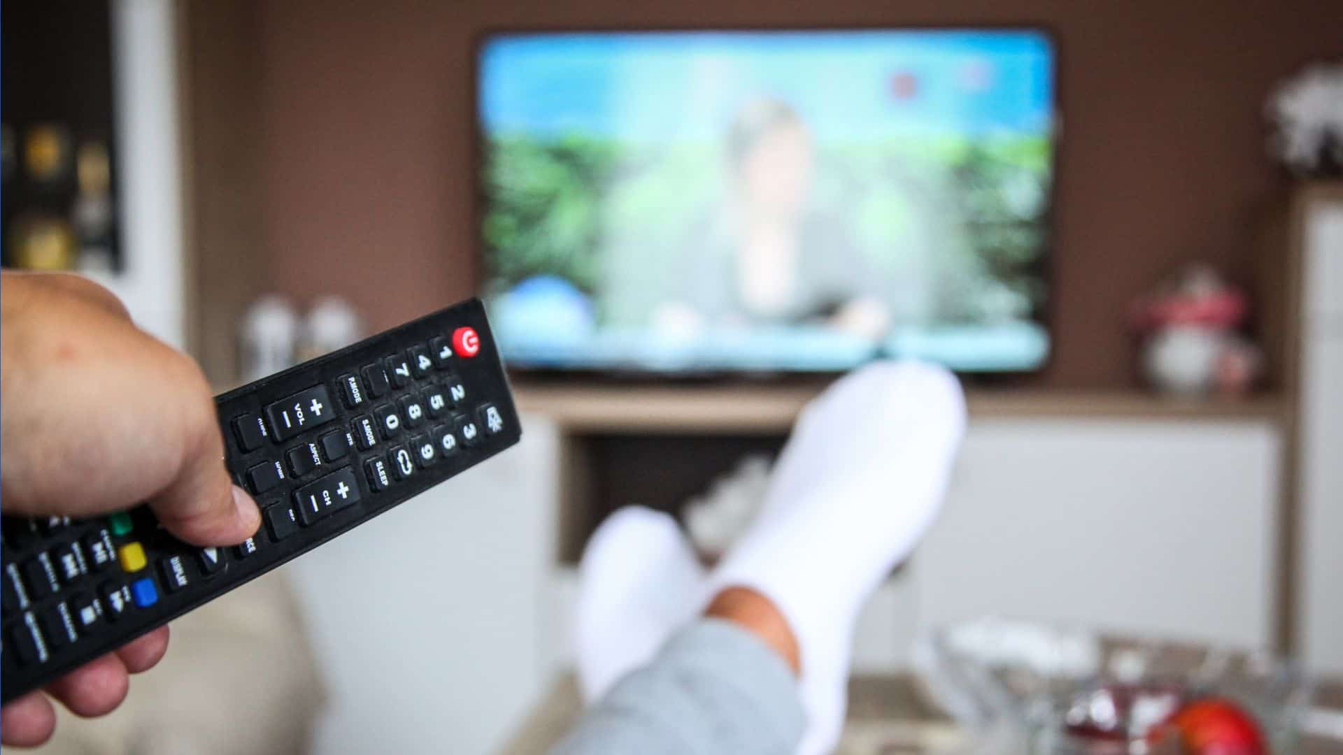 person-watching-tv-remote-in-hand