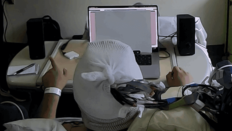 A study participant sits at a desk between two speakers during a Columbia experiment on brain-controlled hearing technology
