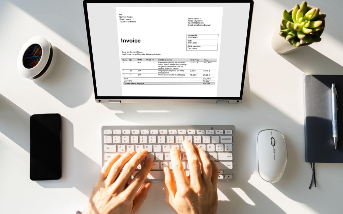 Person creating an invoice on a laptop at a desk