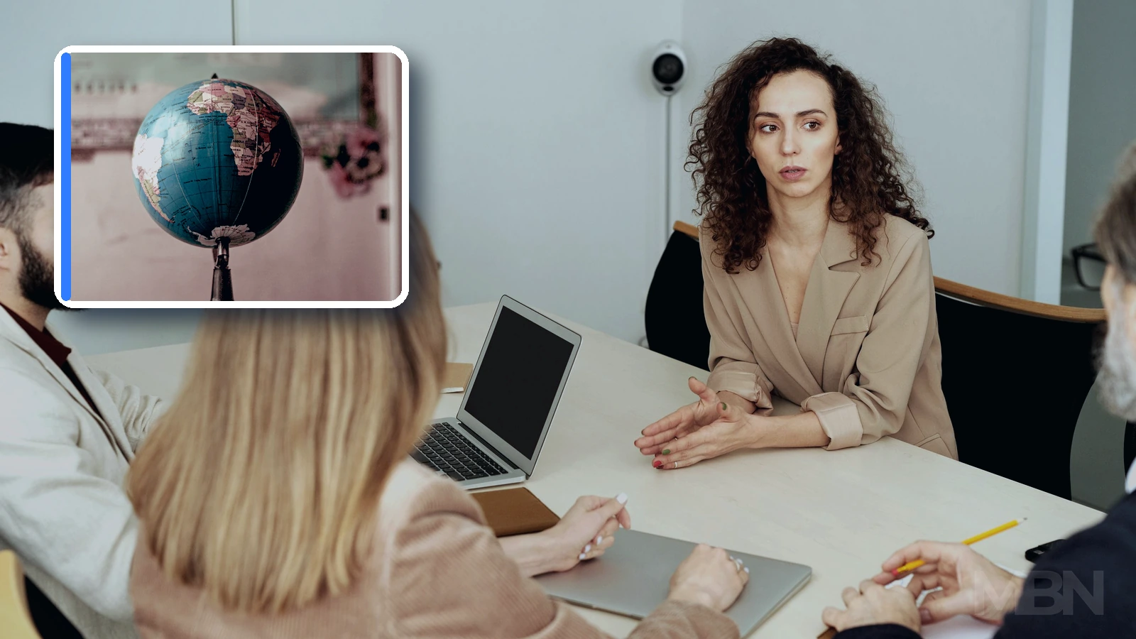 Editorial composite showing colleagues in an office meeting, with a framed globe and world map inset.