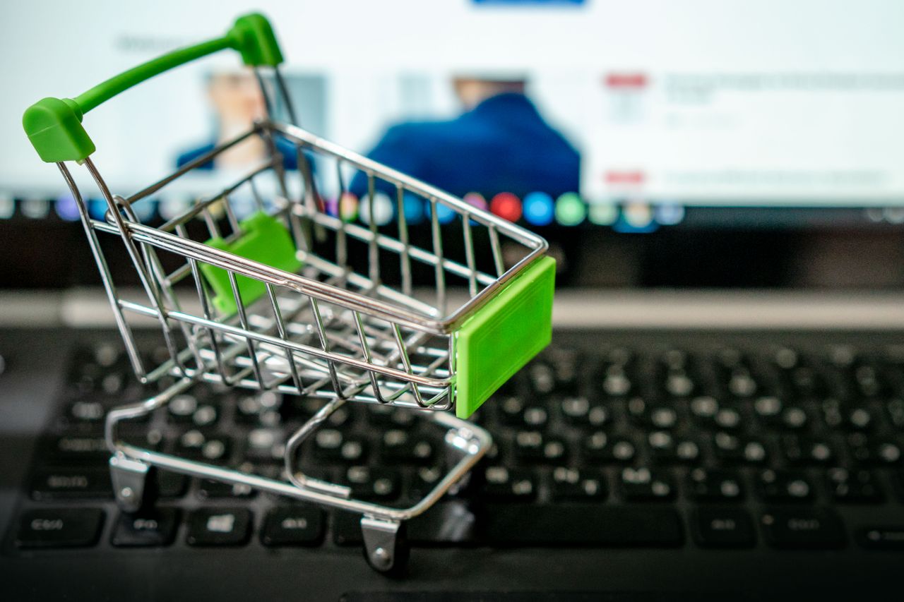 Miniature shopping cart placed on a laptop keyboard