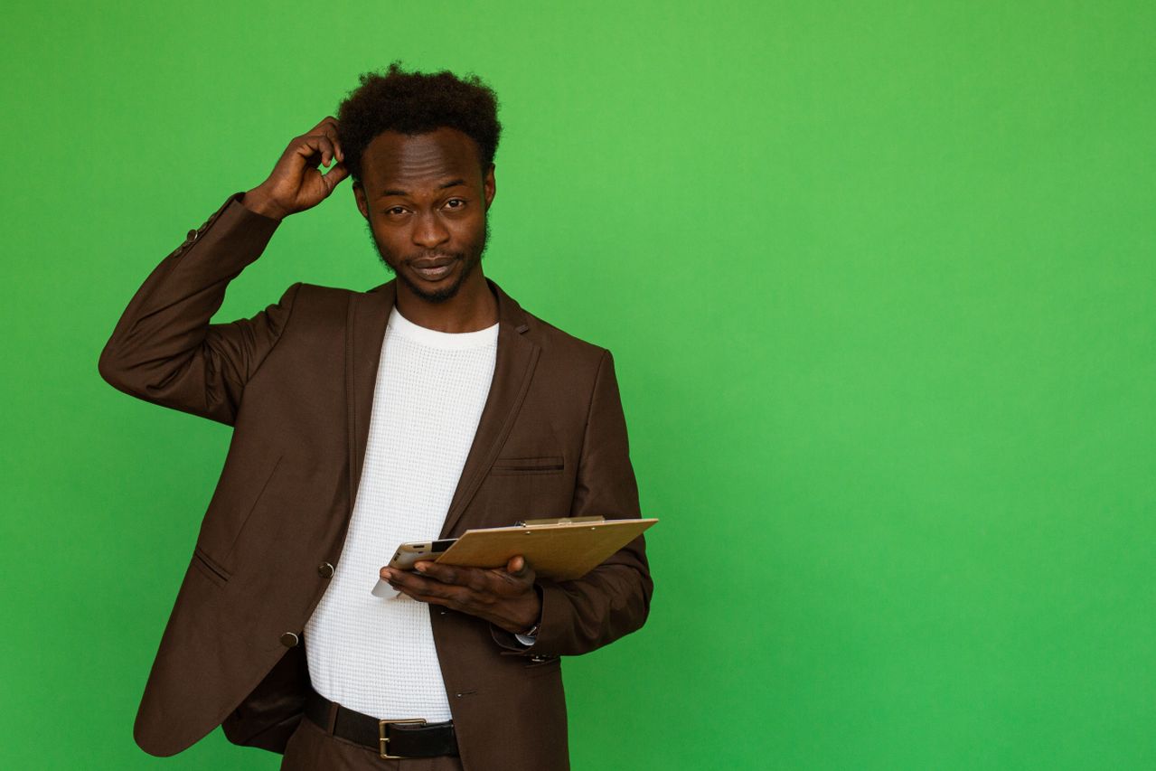 man scratching his head while holding a clipboard