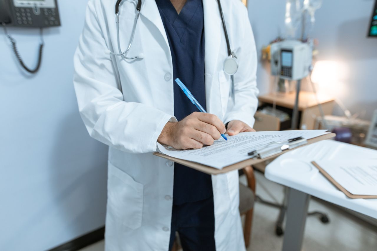 doctor in a lab coat writing notes in a hospital setting