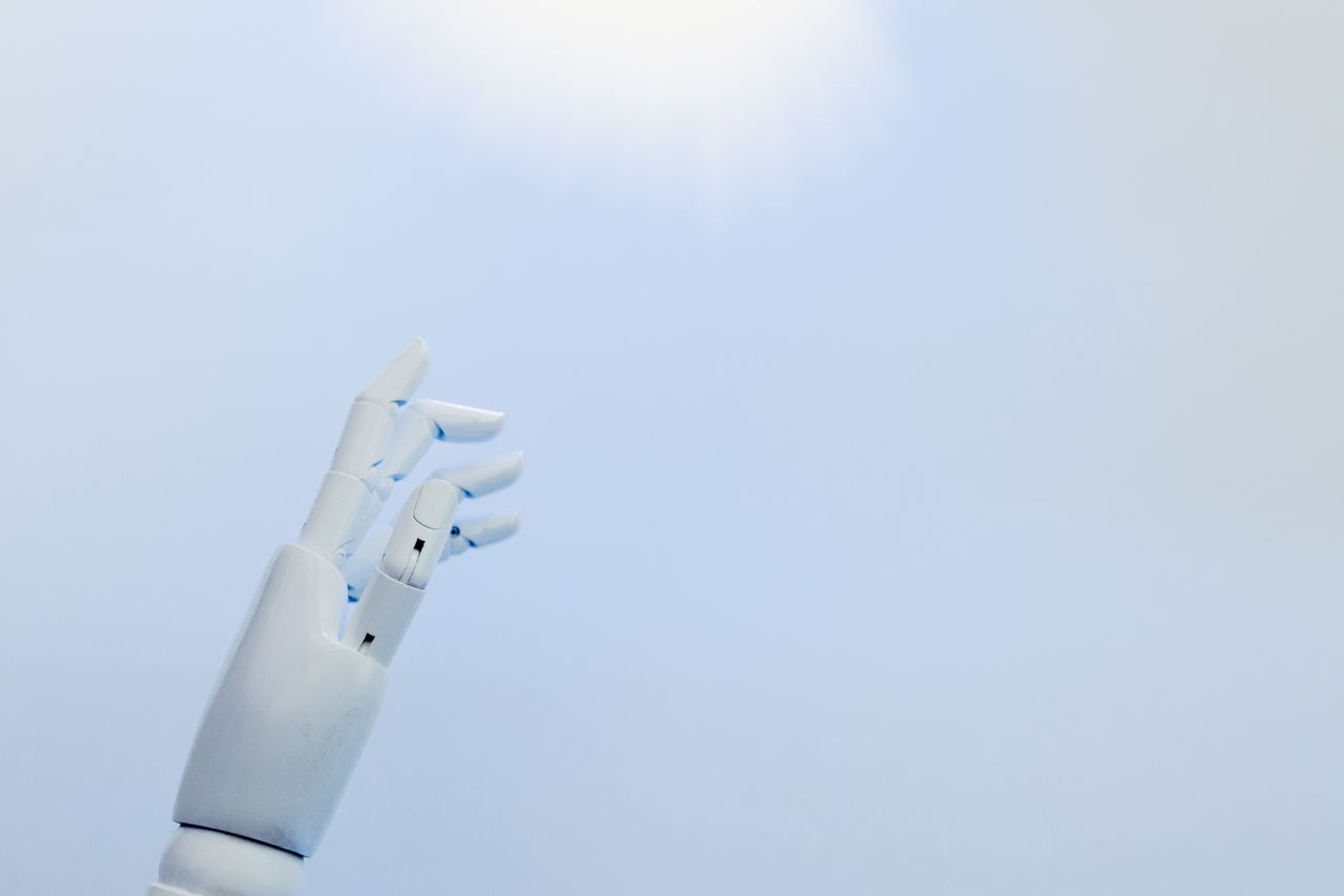 A robotic hand reaching towards a bright light on a white background