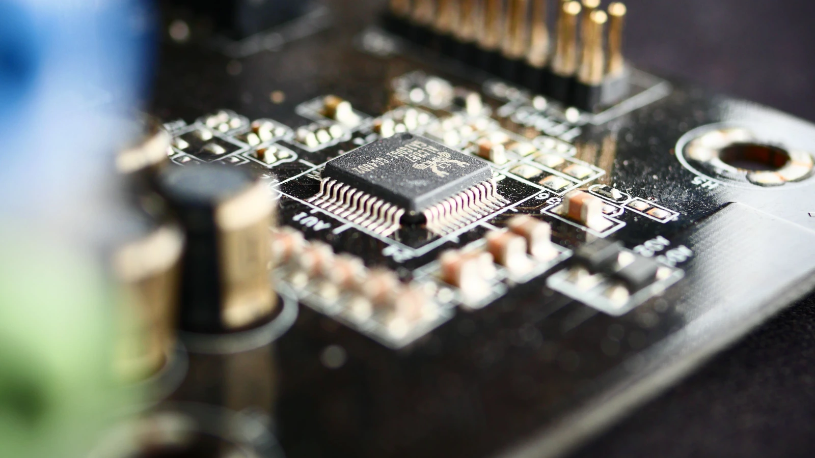 Close-up of a microchip and small components on a circuit board, representing semiconductor hardware; photograph by Rūdolfs Klintsons/Pexels.