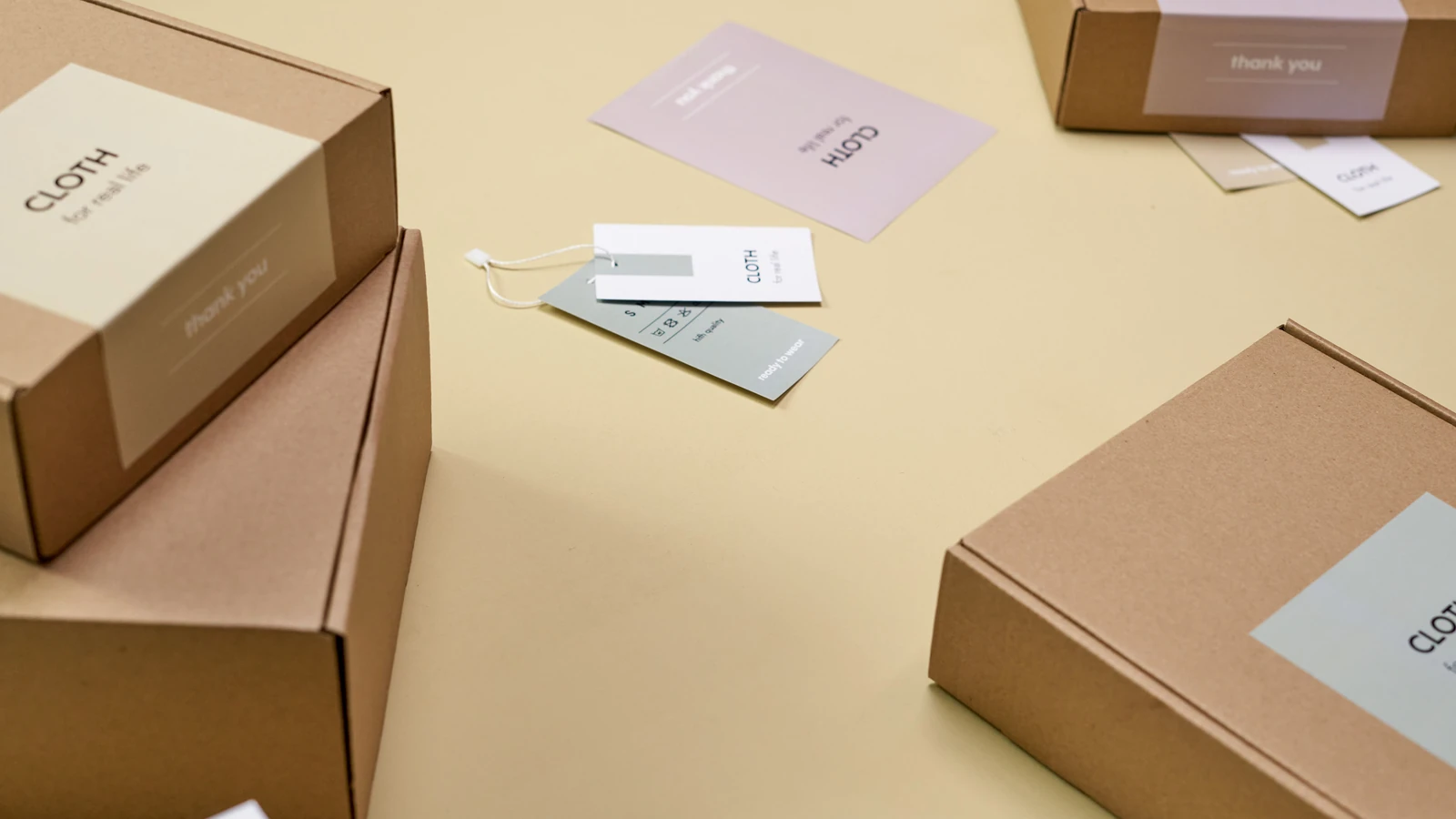 Brown packaging boxes with printed labels and hang tags on a yellow surface, a representative stock photograph by Ron Lach/Pexels.
