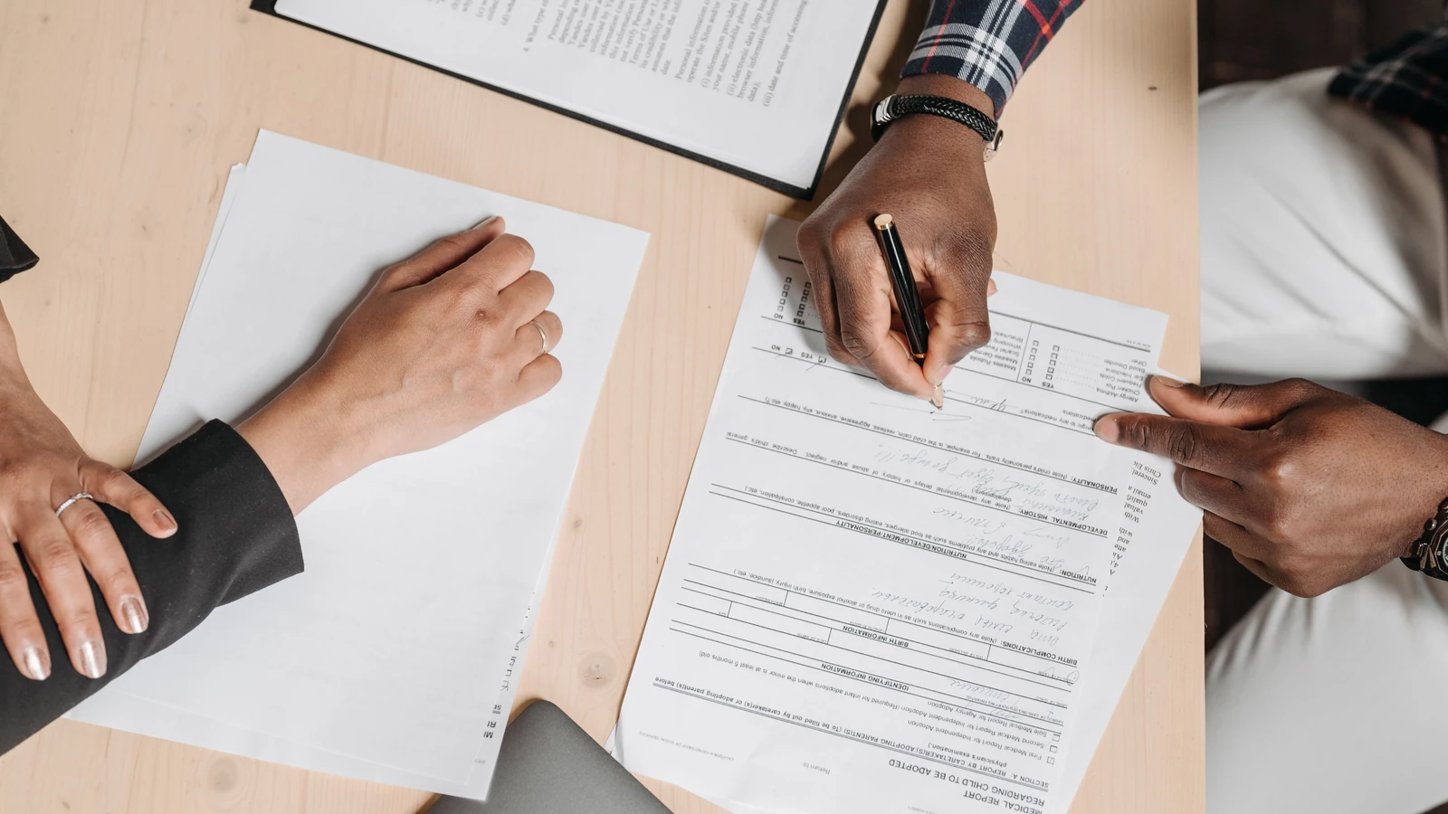 Two people reviewing and completing paper forms at a desk, a representative stock photograph by Pavel Danilyuk from Pexels.