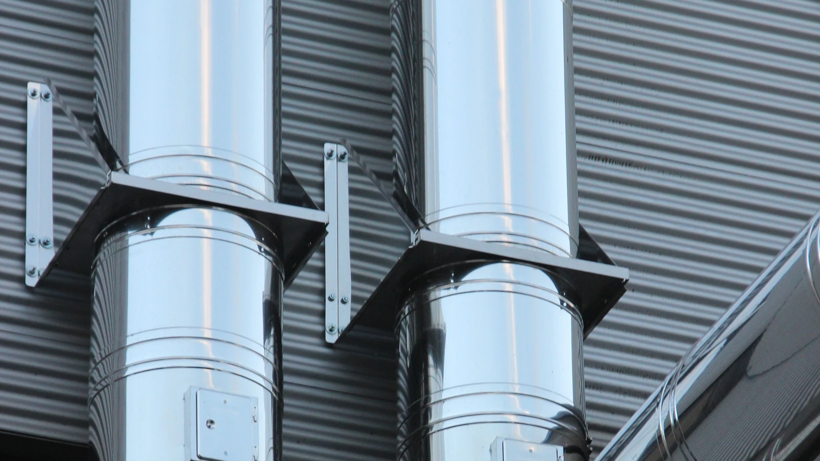 Metal ventilation ducts attached to an industrial building, a representative stock photograph credited to Pixabay via Pexels under CC0.