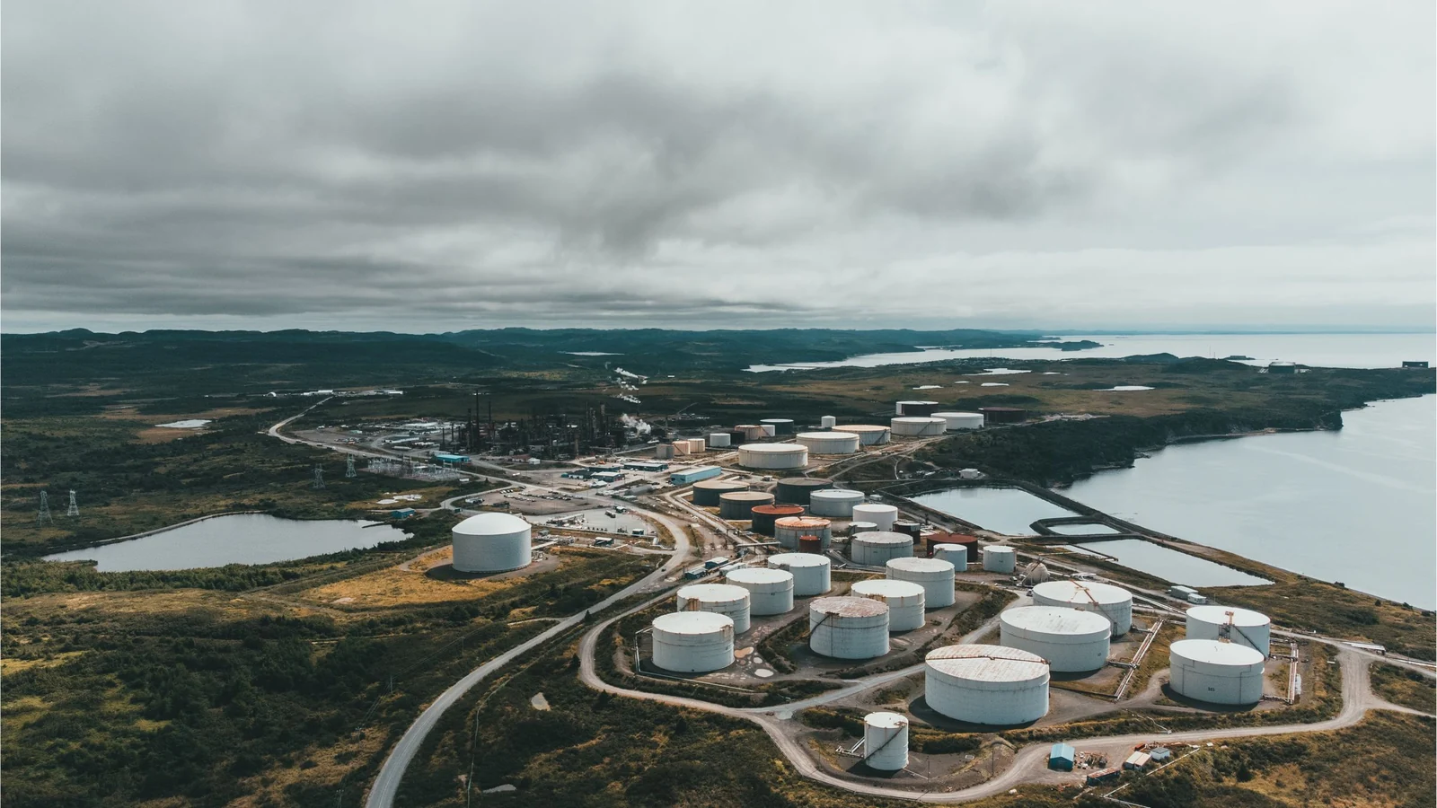 Oil storage tanks beside water, a representative stock photograph by Erik Mclean/Pexels.