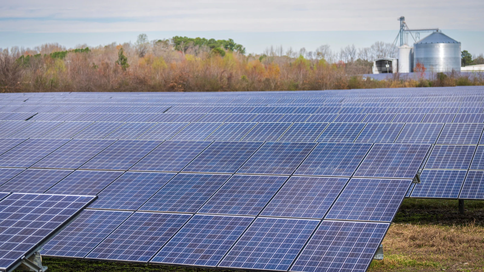 Rows of solar panels near agricultural buildings, representative stock photography by Mark Stebnicki from Pexels under the Pexels License.