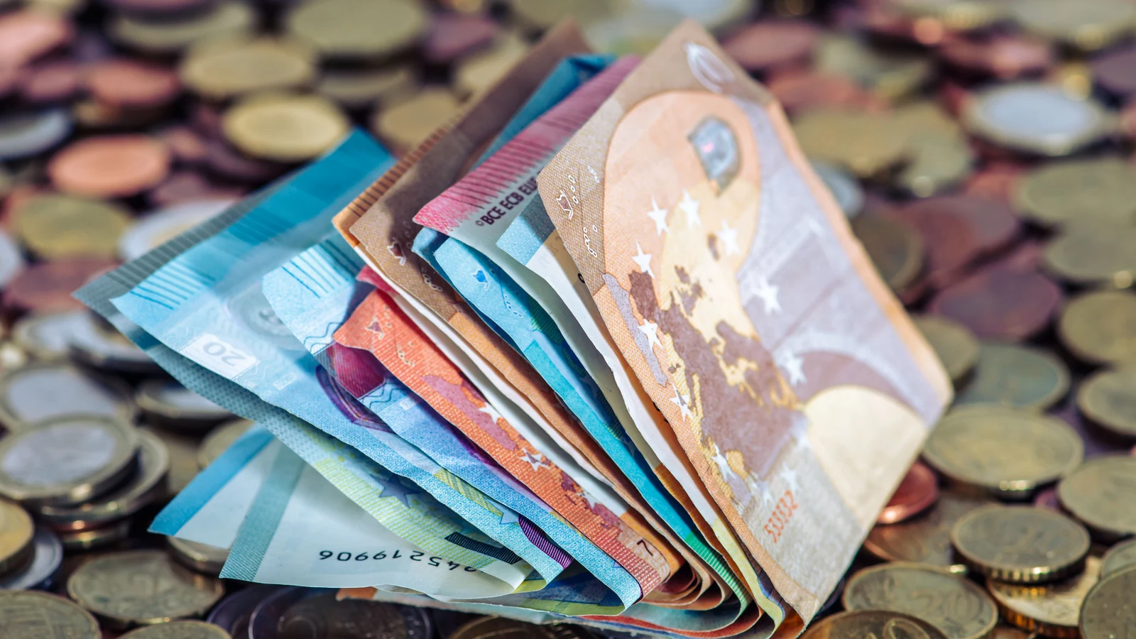 Folded euro banknotes beside scattered coins on a table, a representative currency photograph by Willfried Wende from Pexels, cropped for the cover.