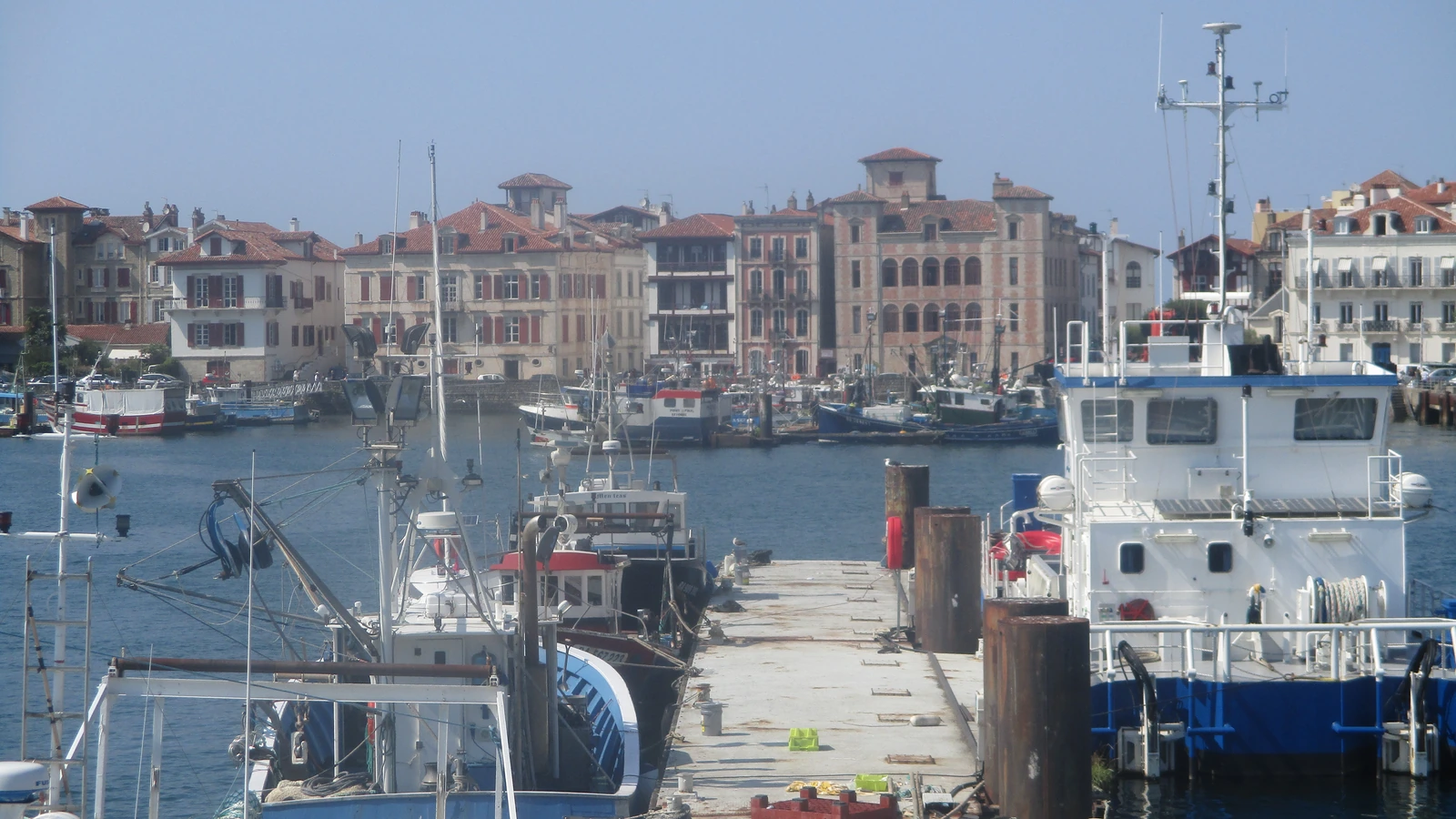 Fishing boats moored in the harbour at Saint-Jean-de-Luz, France, with waterfront buildings behind them.