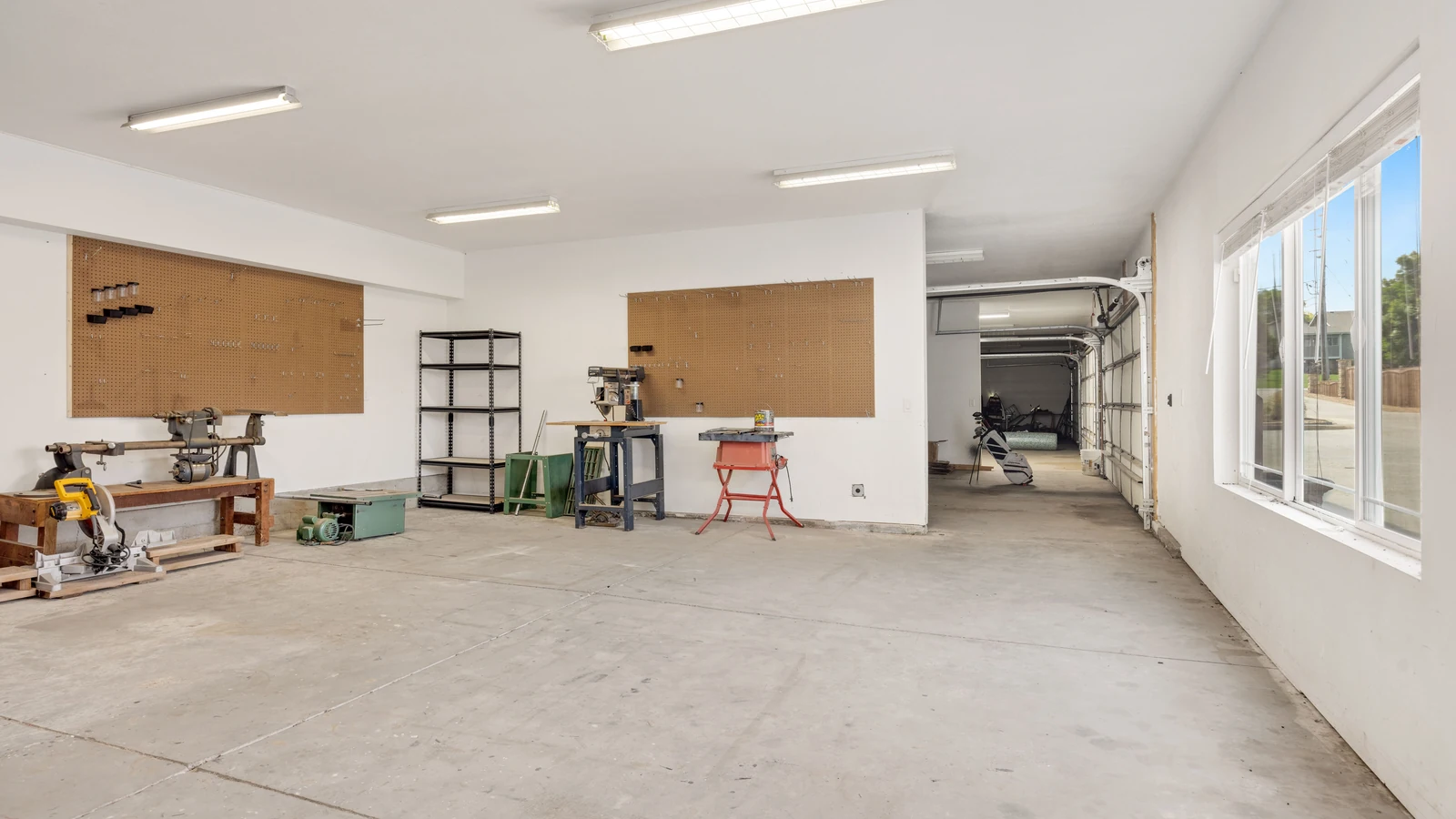 Machinery and workbenches line a bright workshop with open floor space, a representative stock photograph by hi room/Pexels.