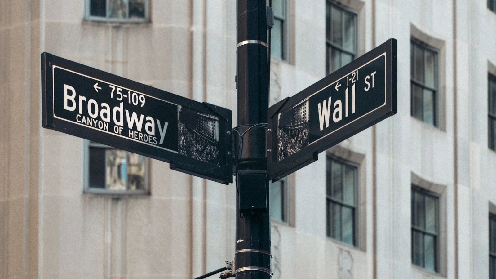 Wall Street and Broadway street signs stand beside buildings in New York, photographed by Mohammed Abubakr for Pexels.