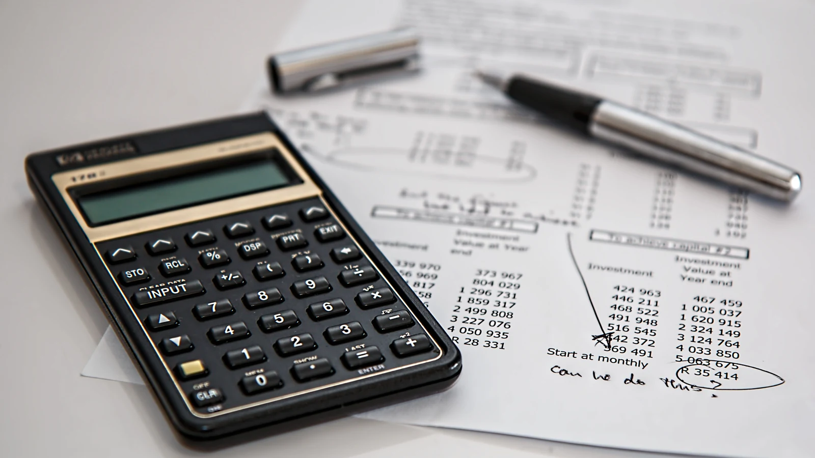 A calculator and pen rest on printed financial documents in a representative business-finance photograph credited to Pixabay via Pexels.