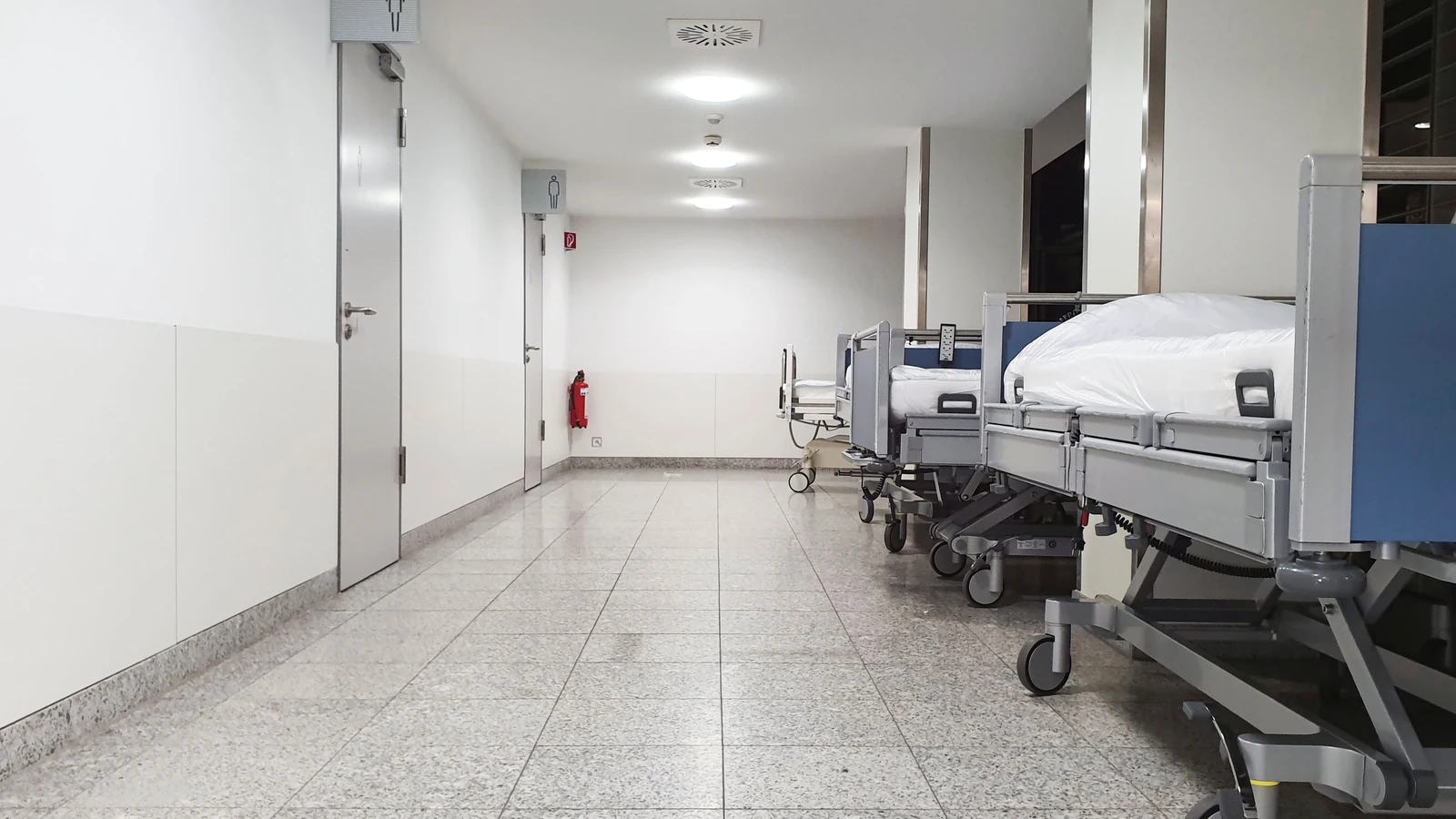 Empty medical beds stand along a healthcare corridor in a representative stock photograph by adrian vieriu/Pexels.