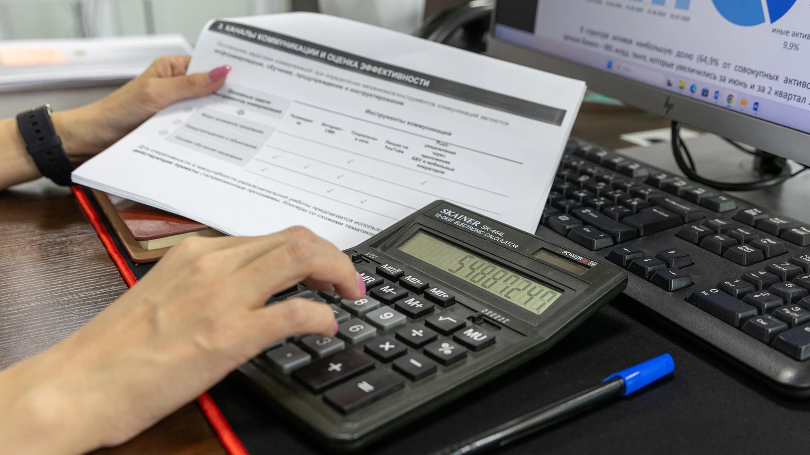 A hand uses a calculator beside a printed financial document on an office desk, a representative stock photograph by Bia Limova/Pexels.