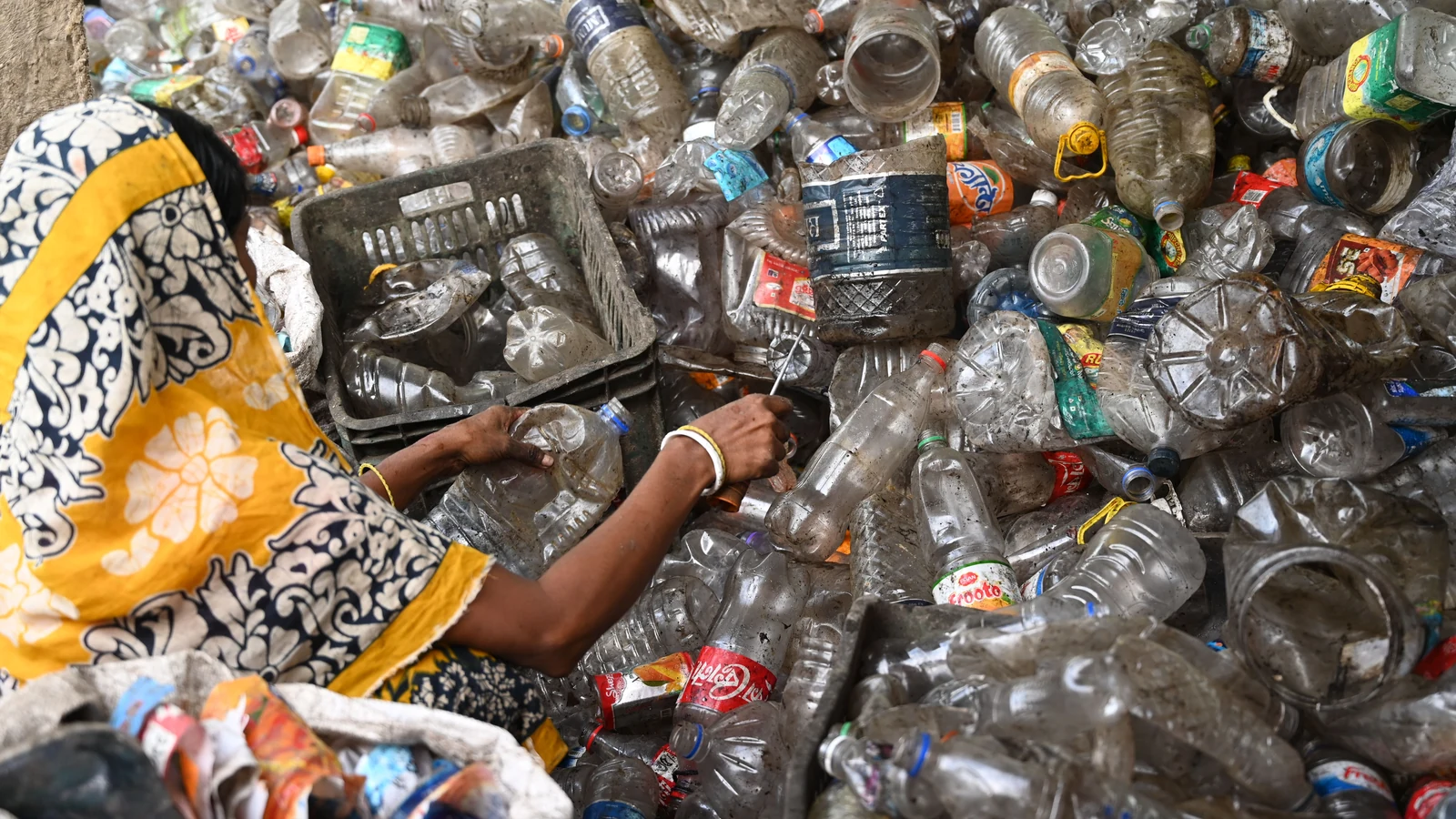 A woman sorts plastic bottles at a recycling center in Bangladesh. Representative stock photograph by Mumtahina Tanni via Pexels.
