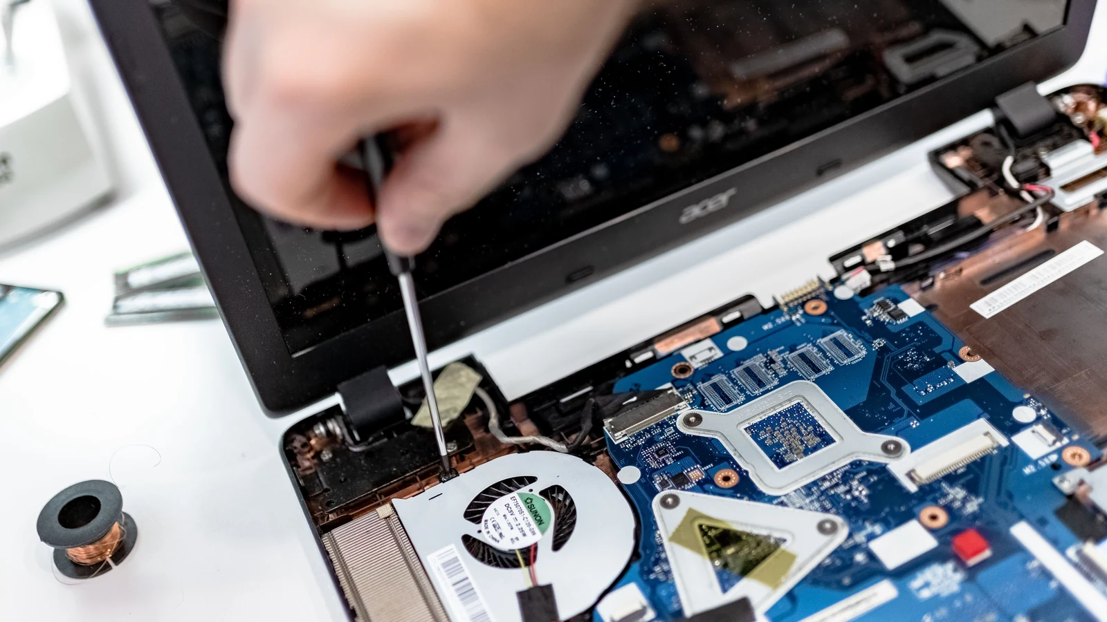 A hand uses a screwdriver on an opened laptop in a representative repair photograph by IT services EU/Pexels.