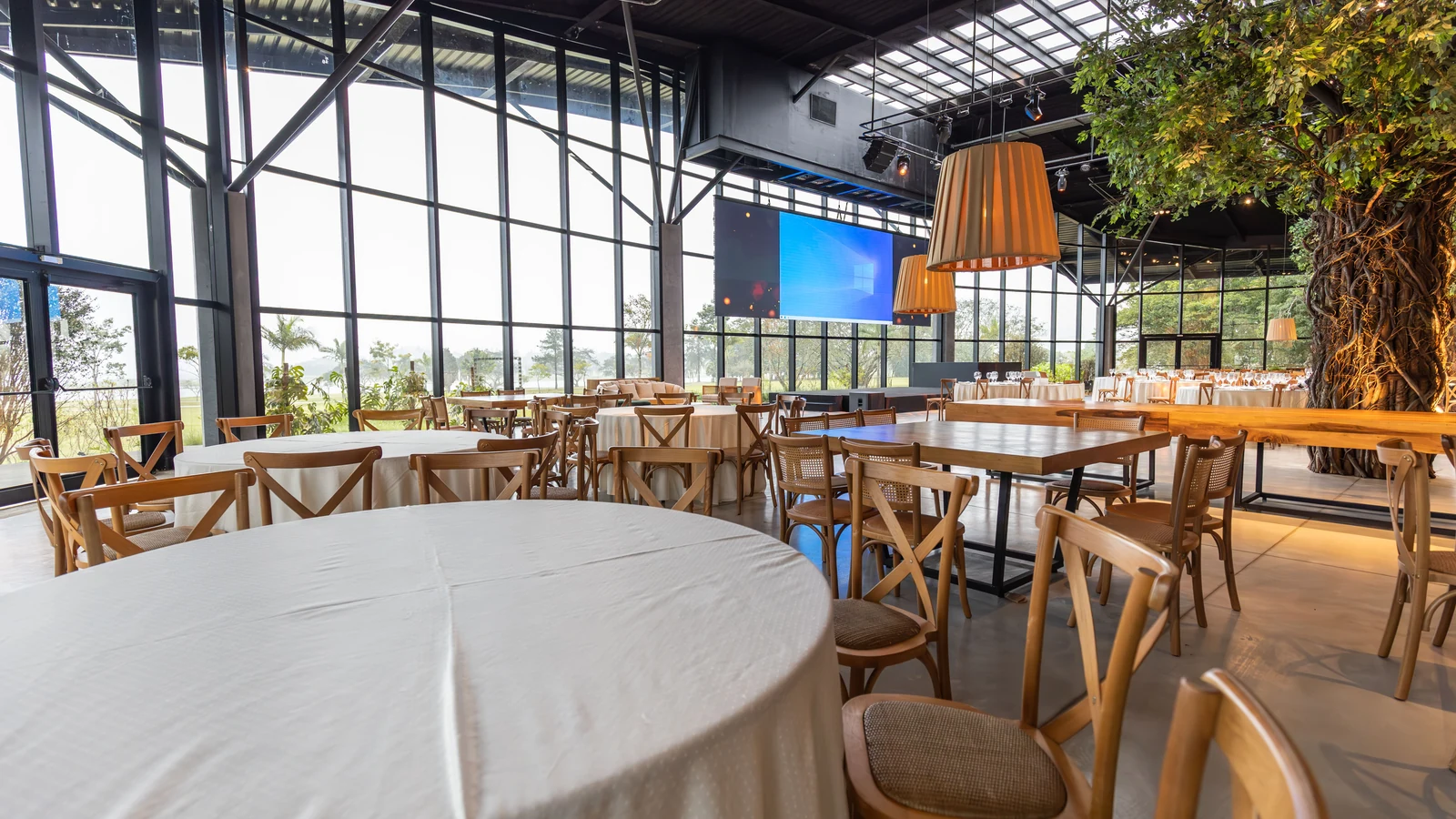Empty restaurant dining room with wooden tables, chairs and large windows, photographed by Matheus Bertelli for Pexels.
