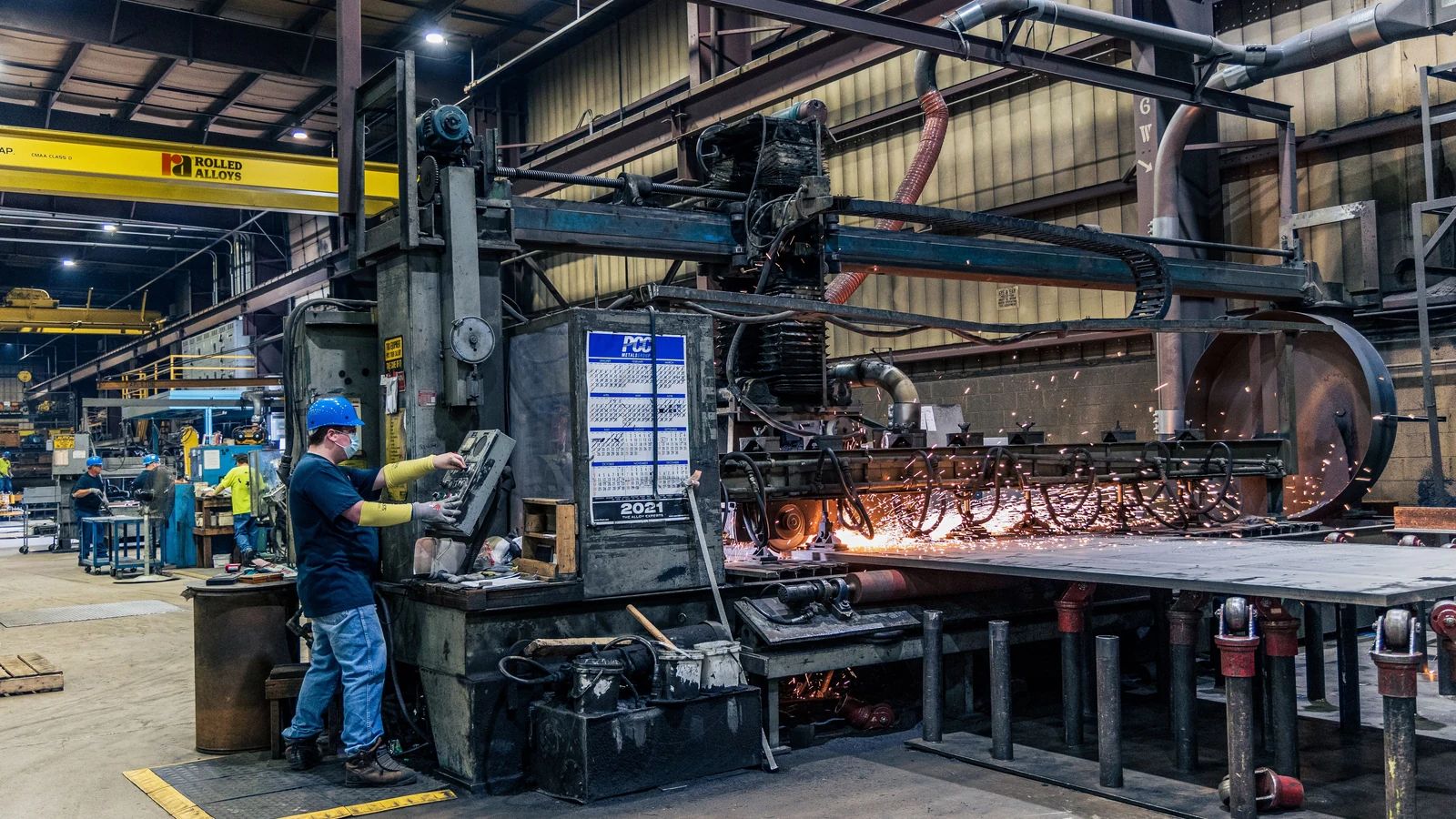 A worker in safety gear operates factory machinery, a representative stock photograph by Rolled Alloys Specialty Metal Supplier via Pexels.