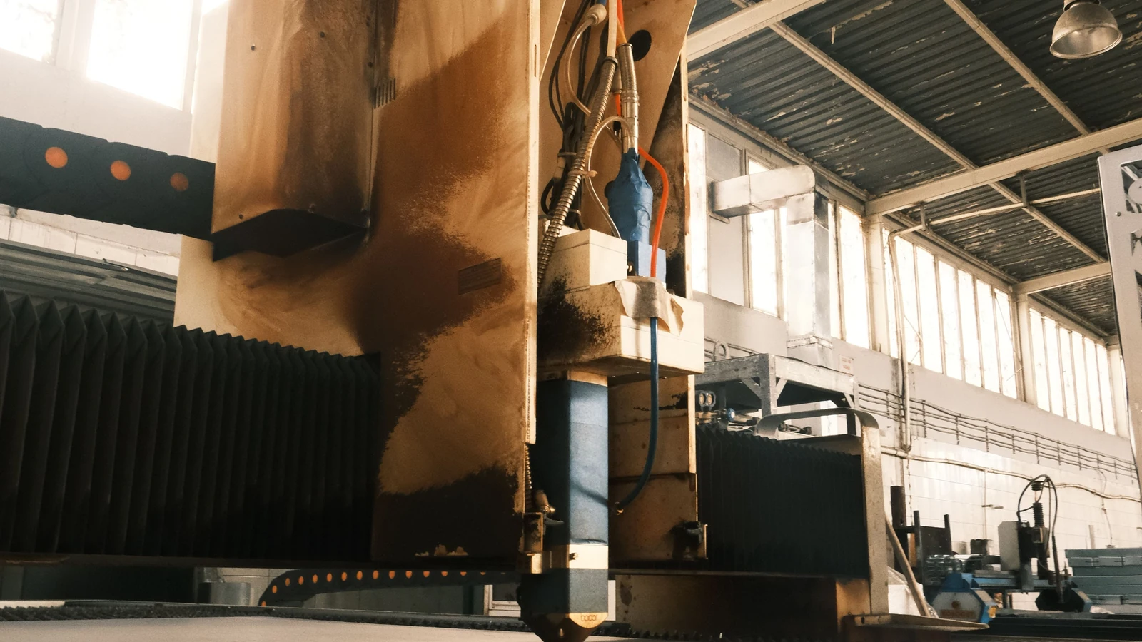 Industrial cutting equipment stands inside a factory building, representative stock photography by Cemrecan Yurtman/Pexels.