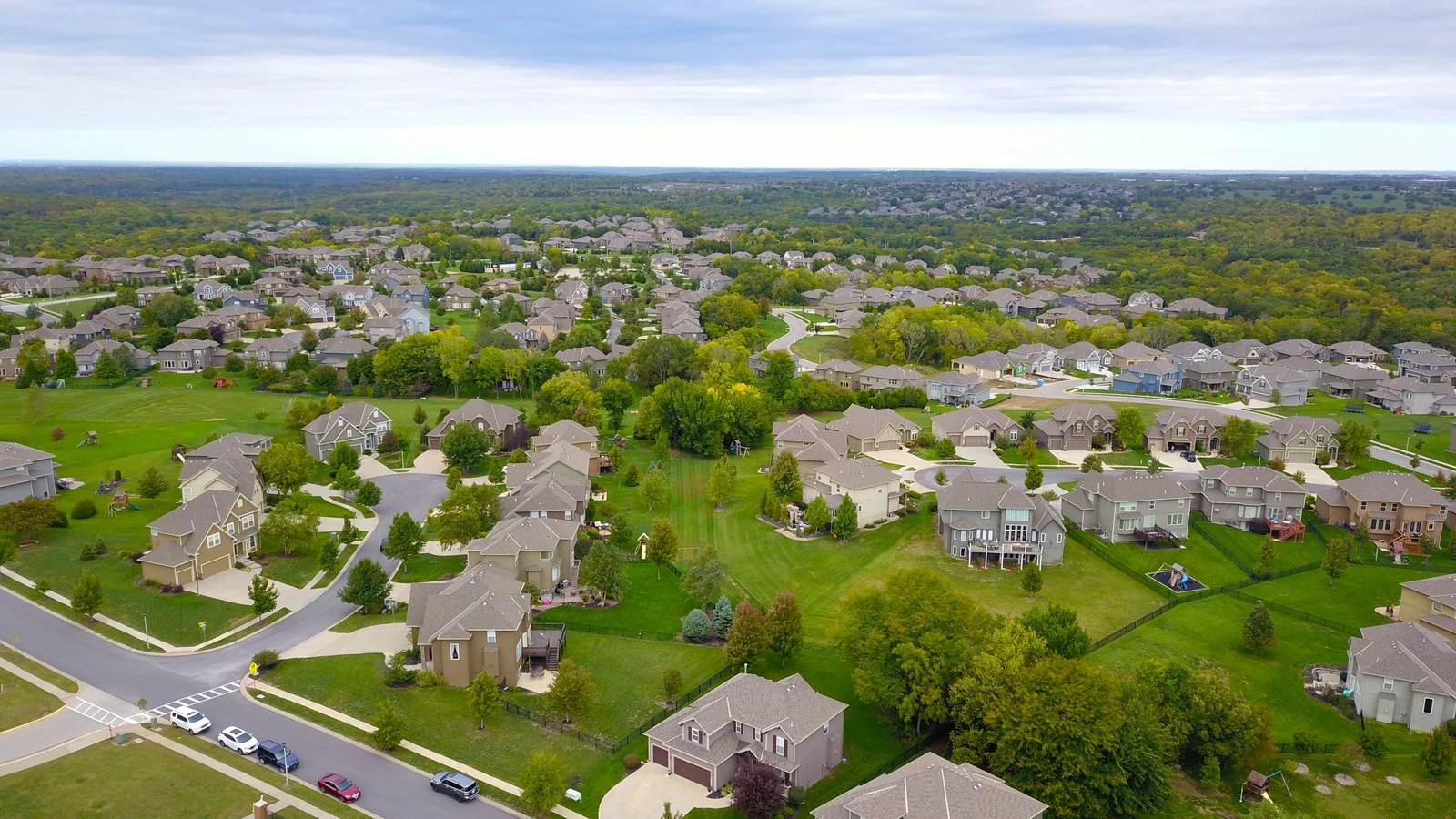 An aerial view of houses, roads and trees in a residential neighborhood, photographed by David McBee for Pexels as a representative insurance image.