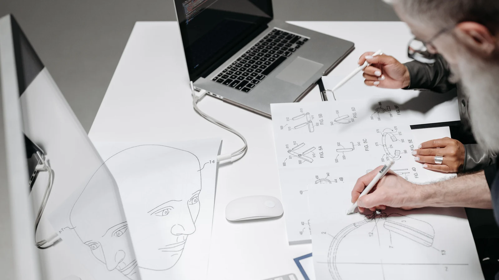 People reviewing technical drawings at a desk, photographed by Pavel Danilyuk for Pexels.