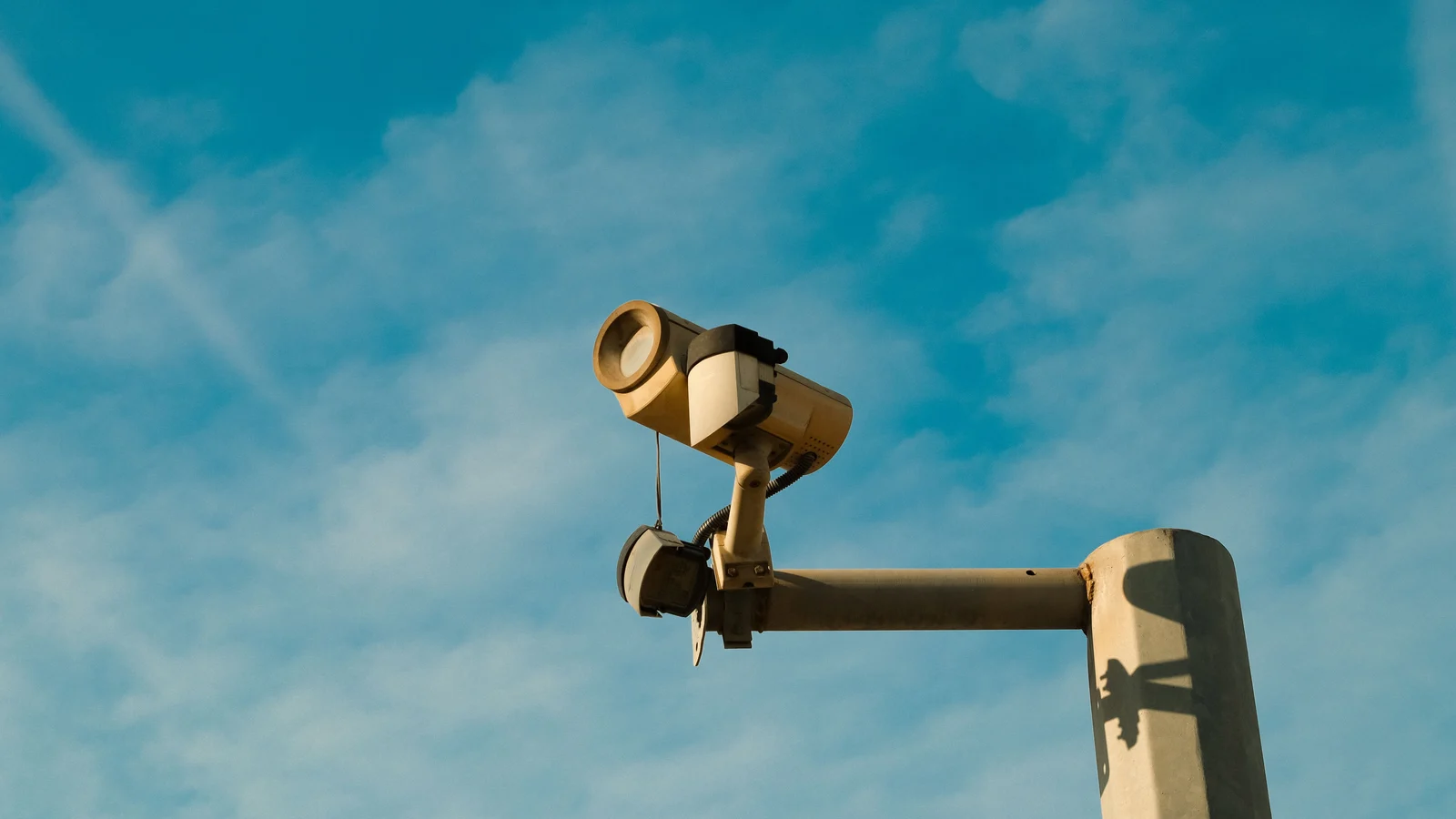 A security camera mounted against a blue sky. Photo: Efe Burak Baydar / Pexels.