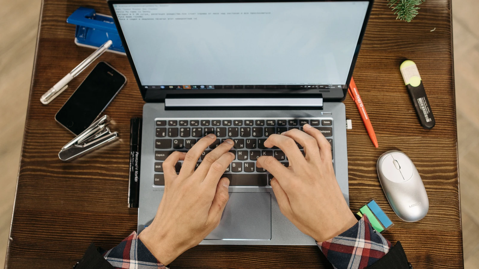 Hands type on a laptop surrounded by office supplies, a representative stock photograph by Pavel Danilyuk/Pexels.