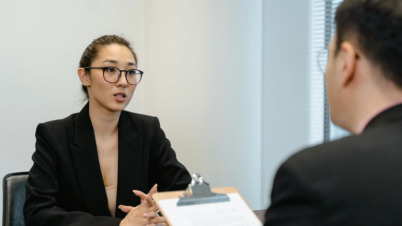 Two people speak across a desk during an office interview, a representative stock photograph by MART PRODUCTION/Pexels.